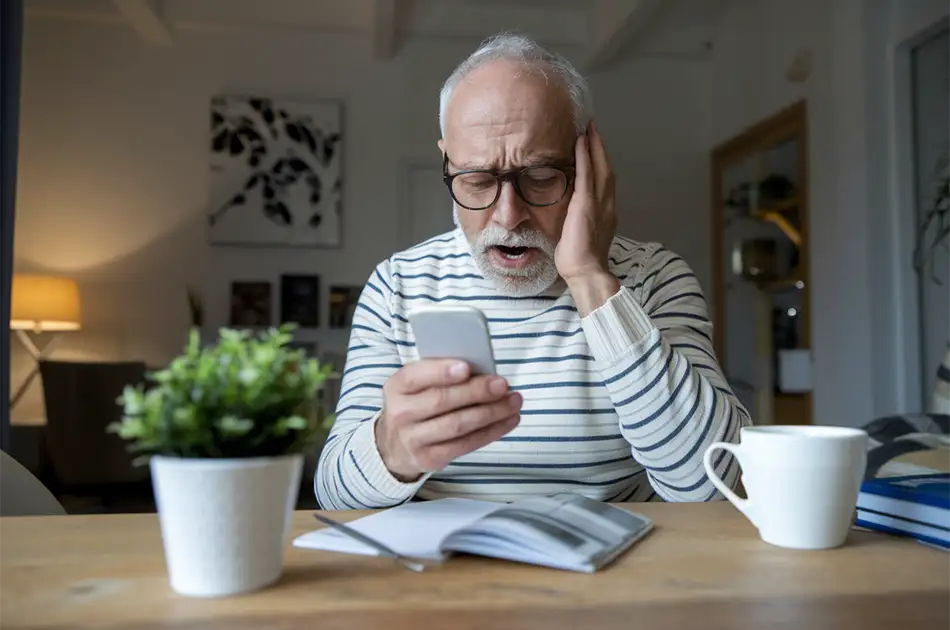 Older gentleman looking at his phone after being scanned