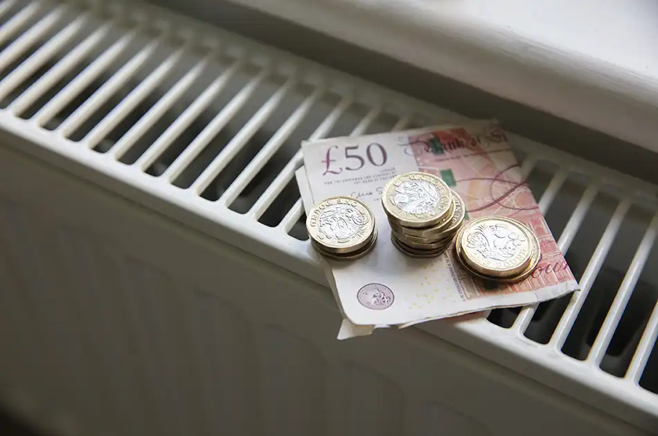 Money on a radiator, a £50 pound notes and some £1 and £2 coins on top